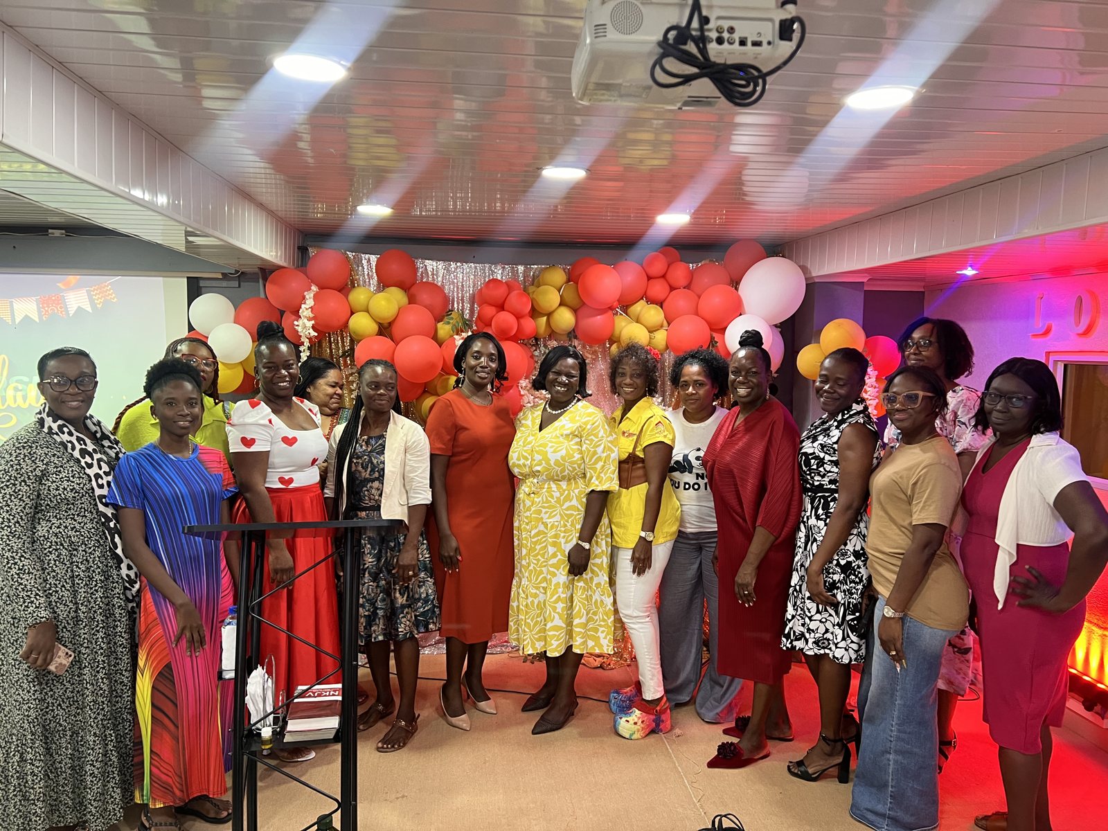 A group of women gathered together in front of a balloon backdrop