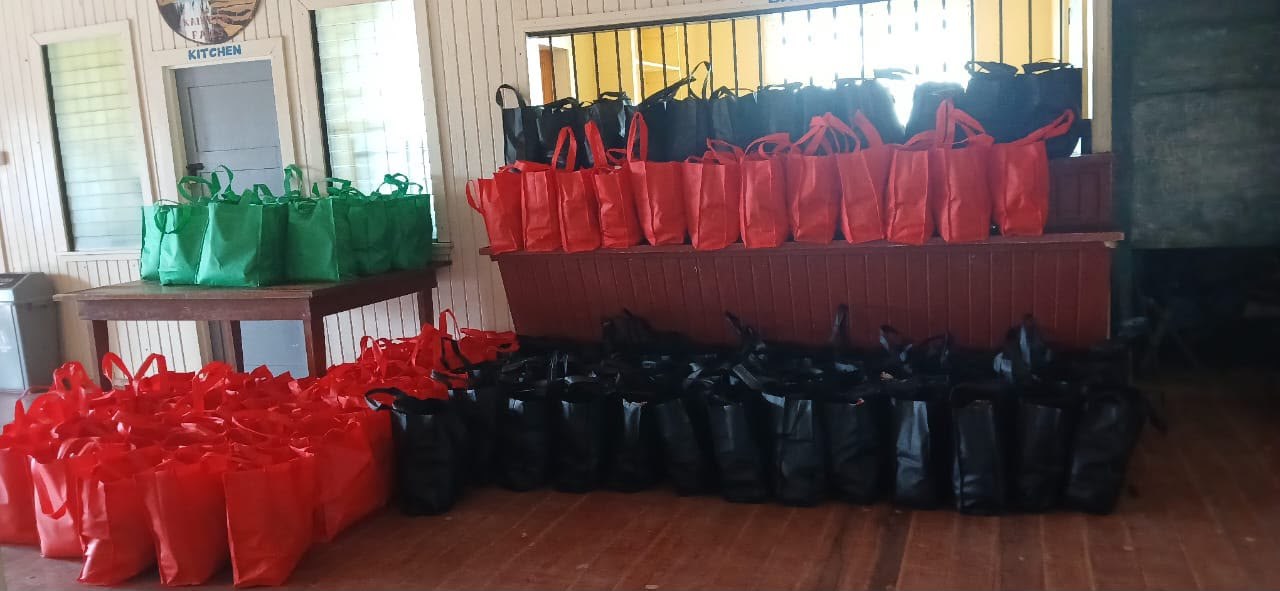 Rows of red, green and black gift bags lined up in a hall, ready to be given to families